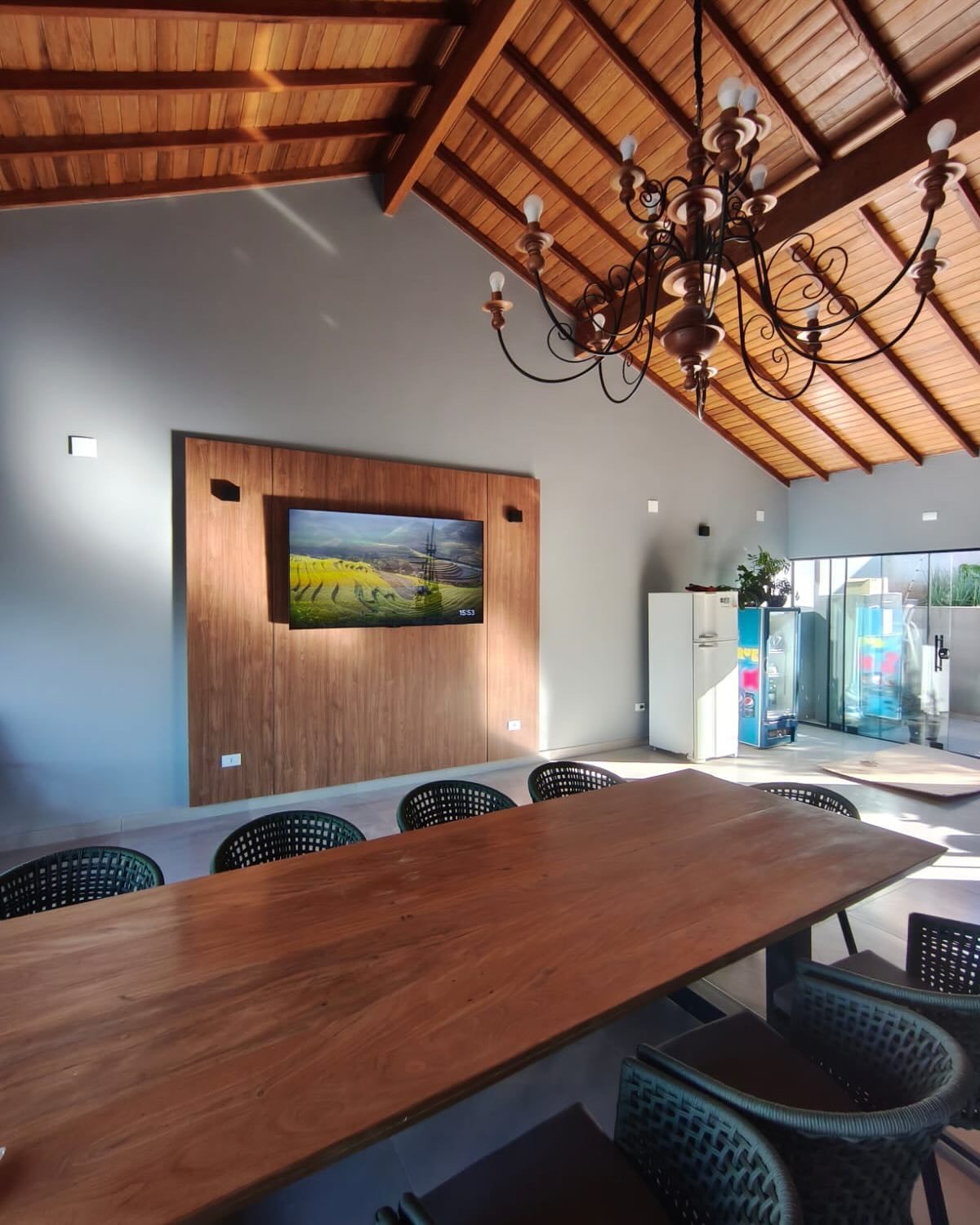 Sala de jantar com painel amadeirado de parede inteira para a TV e forro de madeira